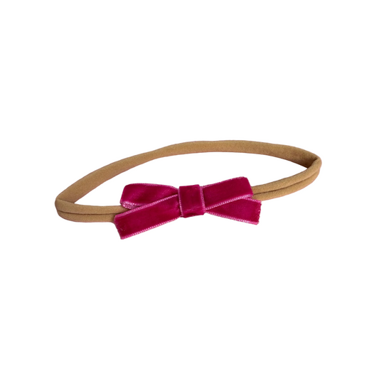 Beige headband with a pink velvet bow on a white background