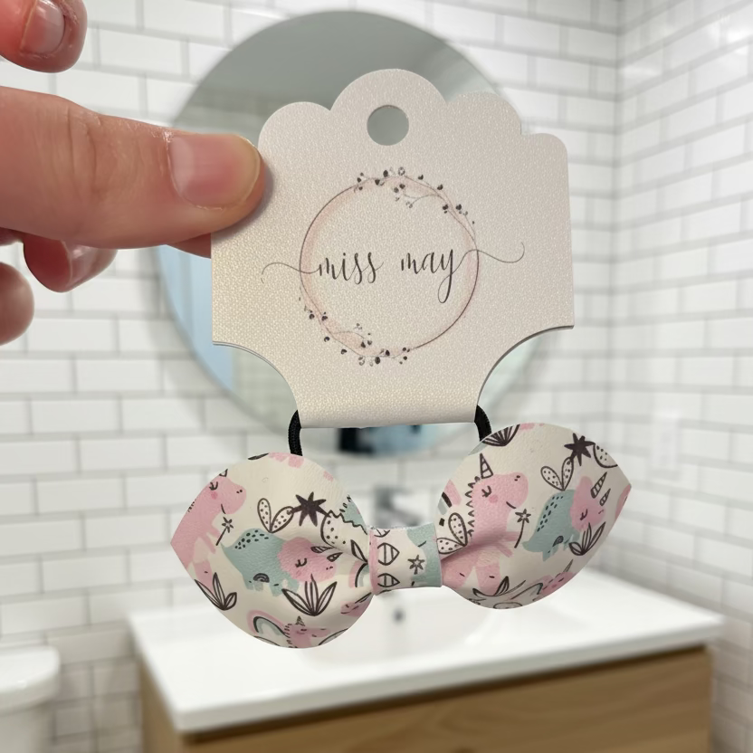 Close up of pink and mint dinosaur unicorn patterned hair accessory bow